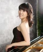 Teacher Helena Kim leaning against a grand piano