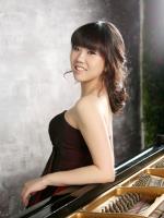 Teacher Helena Kim leaning against a grand piano