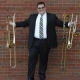 Teacher Josh Omaits holding multiple trombones